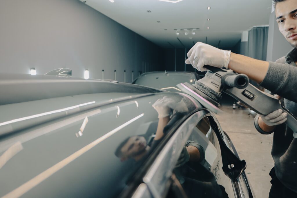 Worker using electric polisher on car roof for a shiny finish in an auto workshop. splash auto zone