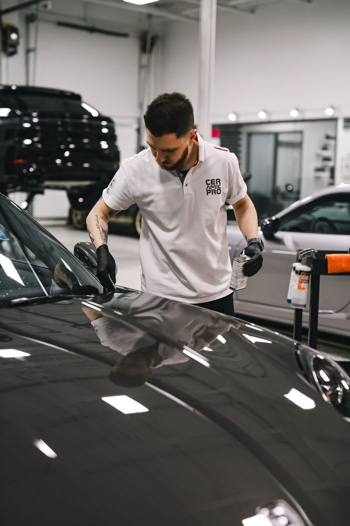 A dedicated employee expertly detailing a car hood in a clean, modern garage setting. splash auto zone