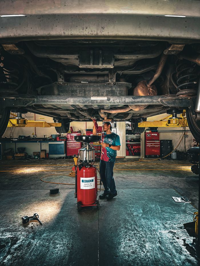 Mechanic inspecting car underside in a professional garage setup. splash auto zone